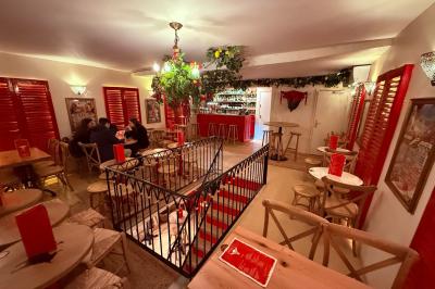 Façade d'un restaurant à l'éclairage rouge vif, avec une entrée ouverte et des décorations florales au-dessus.