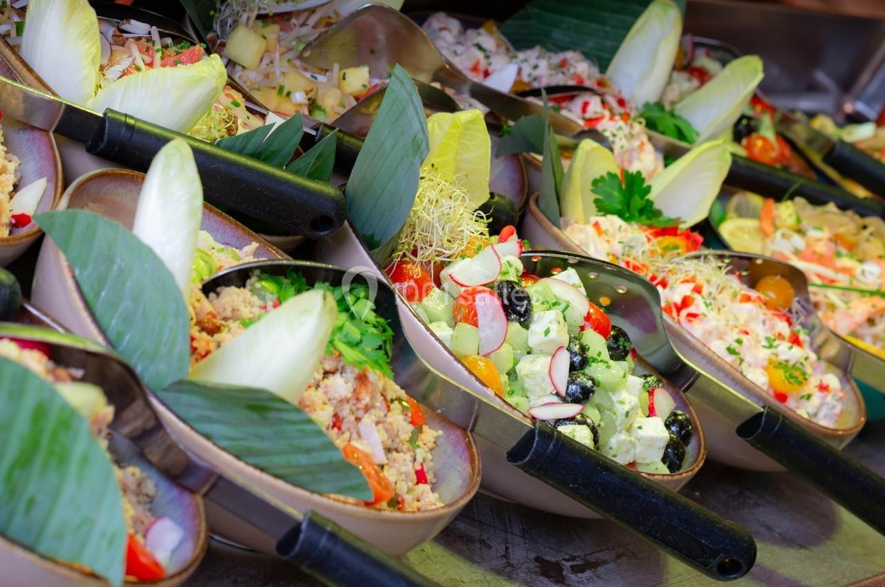 Assortiment de salades colorées présentées dans des bols avec des garnitures fraîches et des feuilles décoratives.