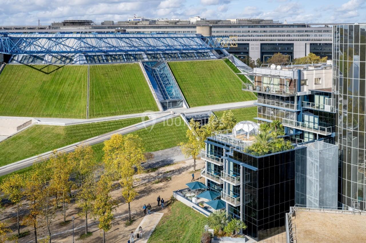 Vue d'un bâtiment moderne avec terrasses végétalisées, entouré d'espaces verts et d'une architecture contemporaine.