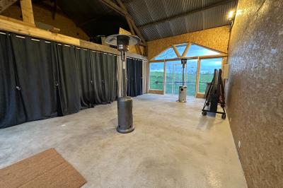 Intérieur d'une pièce avec grandes baies vitrées, murs en bois, un chauffage mobile et un conteneur bleu.