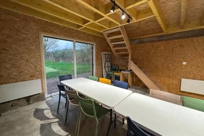 Intérieur d'une pièce avec grandes baies vitrées, murs en bois, un chauffage mobile et un conteneur bleu.