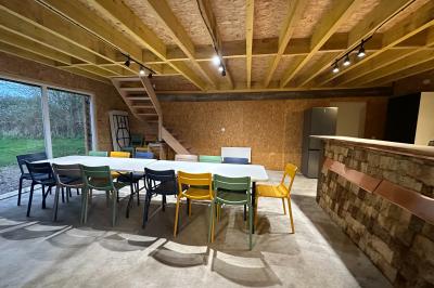 Intérieur d'une pièce avec grandes baies vitrées, murs en bois, un chauffage mobile et un conteneur bleu.