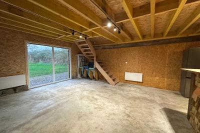 Intérieur d'une pièce avec grandes baies vitrées, murs en bois, un chauffage mobile et un conteneur bleu.