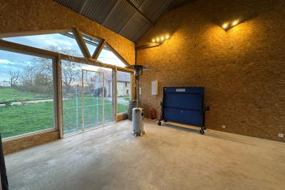 Intérieur d'une pièce avec grandes baies vitrées, murs en bois, un chauffage mobile et un conteneur bleu.