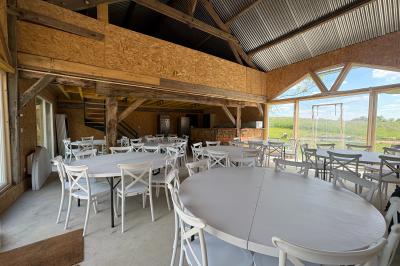 Cuisine ouverte avec plan de travail en bois, armoires vertes, éclairage au plafond et poutres apparentes.