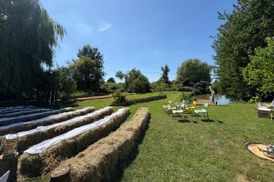Cuisine ouverte avec plan de travail en bois, armoires vertes, éclairage au plafond et poutres apparentes.