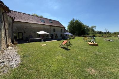 Cuisine ouverte avec plan de travail en bois, armoires vertes, éclairage au plafond et poutres apparentes.