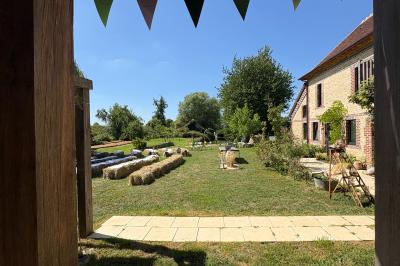 Cuisine ouverte avec plan de travail en bois, armoires vertes, éclairage au plafond et poutres apparentes.