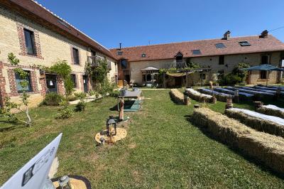 Cuisine ouverte avec plan de travail en bois, armoires vertes, éclairage au plafond et poutres apparentes.