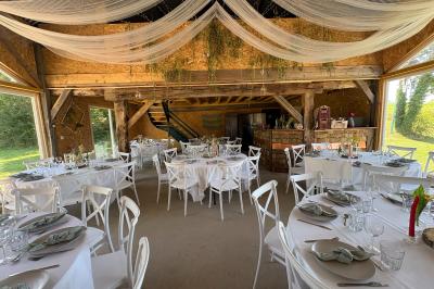 Cuisine ouverte avec plan de travail en bois, armoires vertes, éclairage au plafond et poutres apparentes.