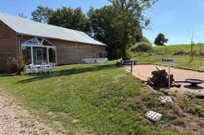 Cuisine ouverte avec plan de travail en bois, armoires vertes, éclairage au plafond et poutres apparentes.