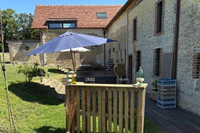 Cuisine ouverte avec plan de travail en bois, armoires vertes, éclairage au plafond et poutres apparentes.