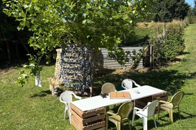 Cuisine ouverte avec plan de travail en bois, armoires vertes, éclairage au plafond et poutres apparentes.