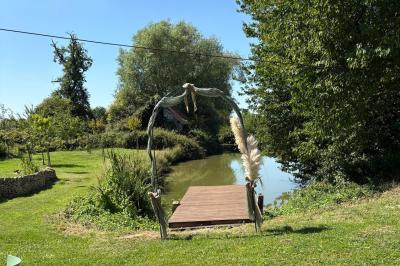 Cuisine ouverte avec plan de travail en bois, armoires vertes, éclairage au plafond et poutres apparentes.