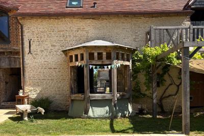 Cuisine ouverte avec plan de travail en bois, armoires vertes, éclairage au plafond et poutres apparentes.