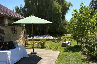 Cuisine ouverte avec plan de travail en bois, armoires vertes, éclairage au plafond et poutres apparentes.