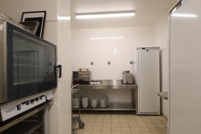 Toilettes accessibles avec barre d'appui, lavabo mural et distributeur de savon dans un espace sombre.