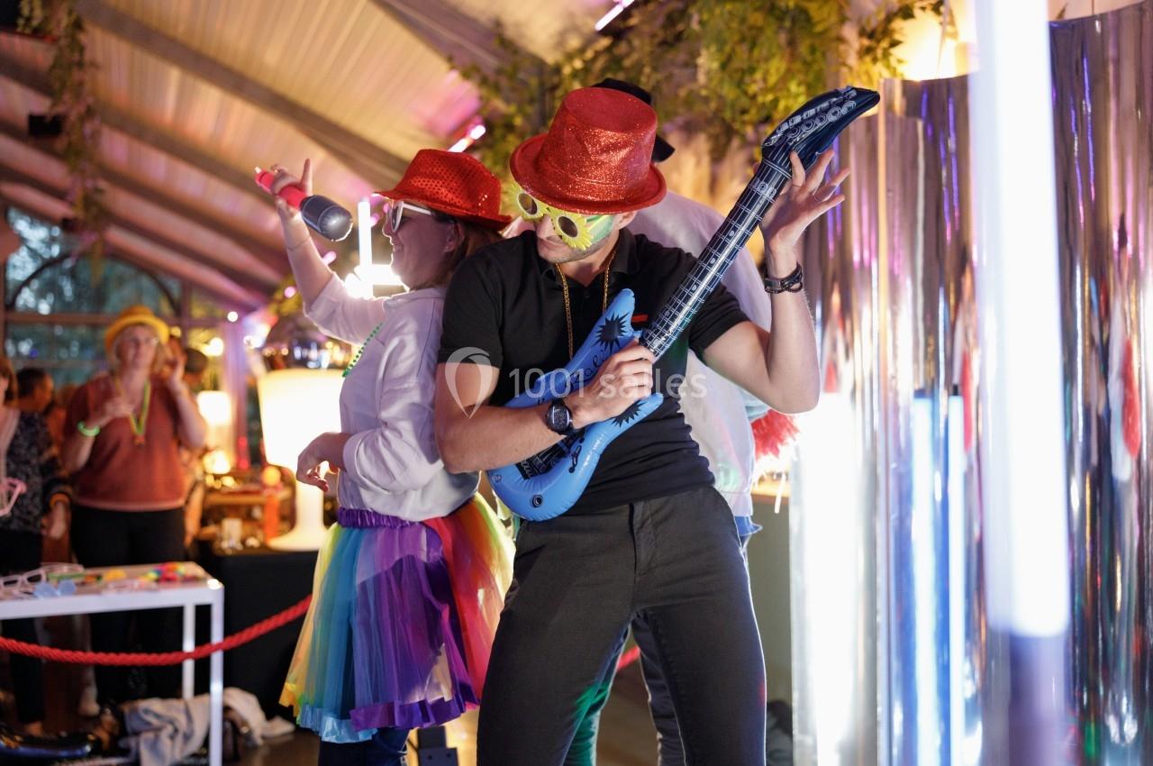 Photo Challenger Event #3 Deux personnes déguisées dansent et jouent avec des accessoires festifs dans un environnement lumineux et animé.