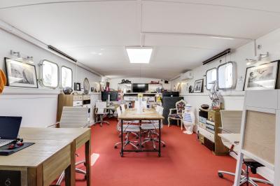 Cuisine professionnelle avec réfrigérateur en inox, four, hotte, étagères murales et plan de travail en acier inoxydable.