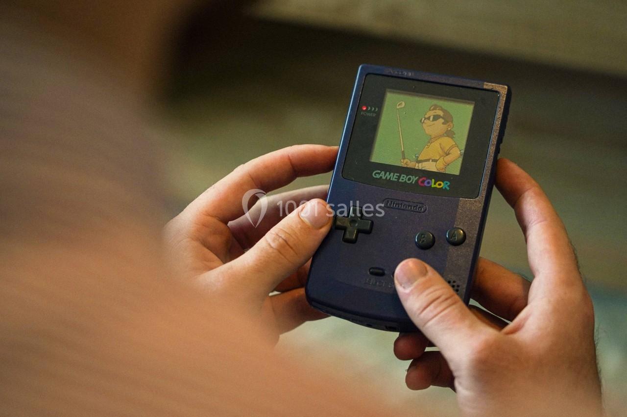 Console portable Game Boy Color violette tenue à deux mains, affichant un jeu de golf sur son écran.