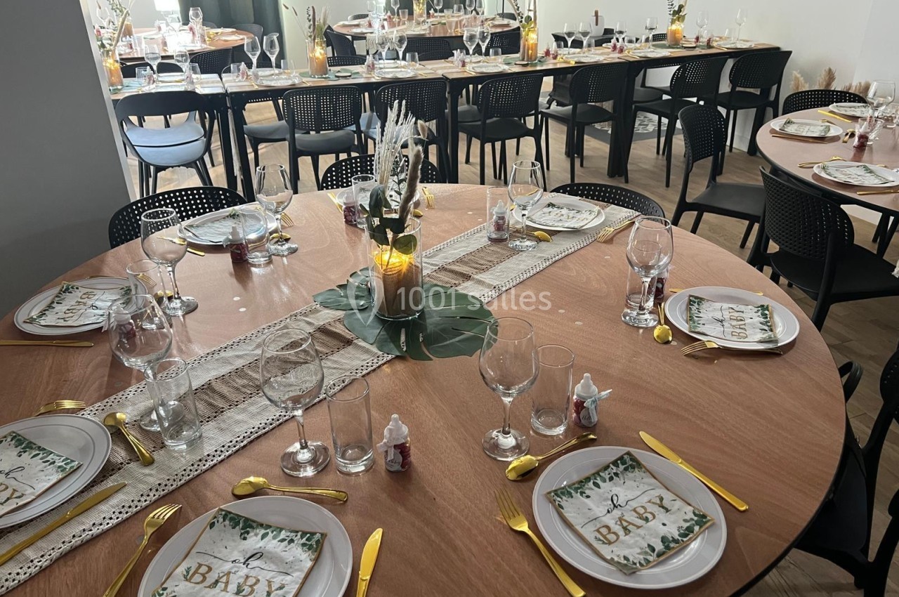 Tables rondes décorées pour un événement, avec vaisselle élégante, couverts dorés et bougies au centre.