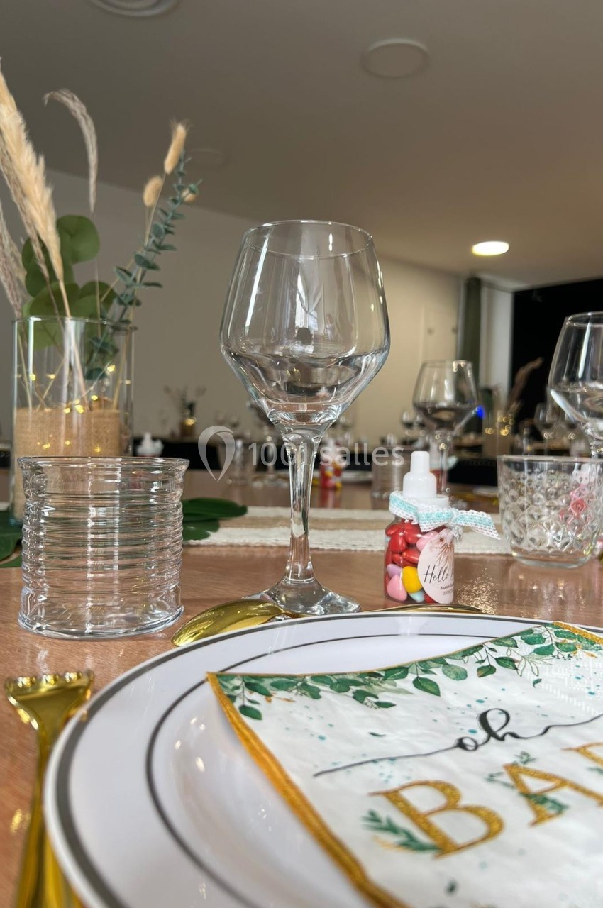 Table dressée avec élégance, comprenant des verres, une assiette décorée ’oh baby’, des couverts dorés et des éléments…