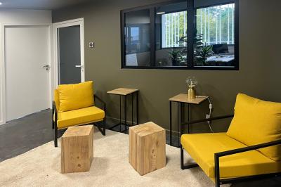 Salle de réception lumineuse avec tables rondes dressées, décorées de fleurs blanches et verdure.