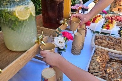 Buffet décoré avec des fleurs, fruits frais, verrines, mini-burgers et desserts, présenté sur une table élégante.