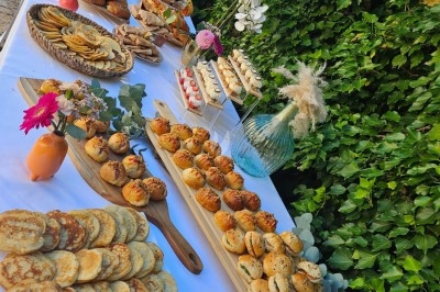 Buffet décoré avec des fleurs, fruits frais, verrines, mini-burgers et desserts, présenté sur une table élégante.