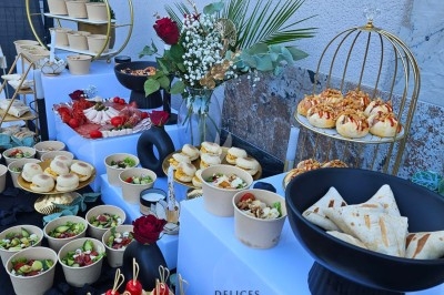 Buffet décoré avec des fleurs, fruits frais, verrines, mini-burgers et desserts, présenté sur une table élégante.
