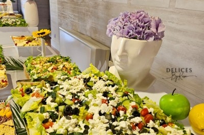 Buffet décoré avec des fleurs, fruits frais, verrines, mini-burgers et desserts, présenté sur une table élégante.