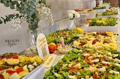 Buffet décoré avec des fleurs, fruits frais, verrines, mini-burgers et desserts, présenté sur une table élégante.