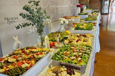 Buffet décoré avec des fleurs, fruits frais, verrines, mini-burgers et desserts, présenté sur une table élégante.