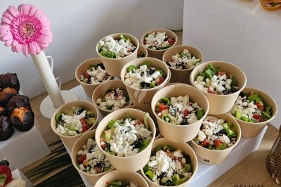 Buffet décoré avec des fleurs, fruits frais, verrines, mini-burgers et desserts, présenté sur une table élégante.