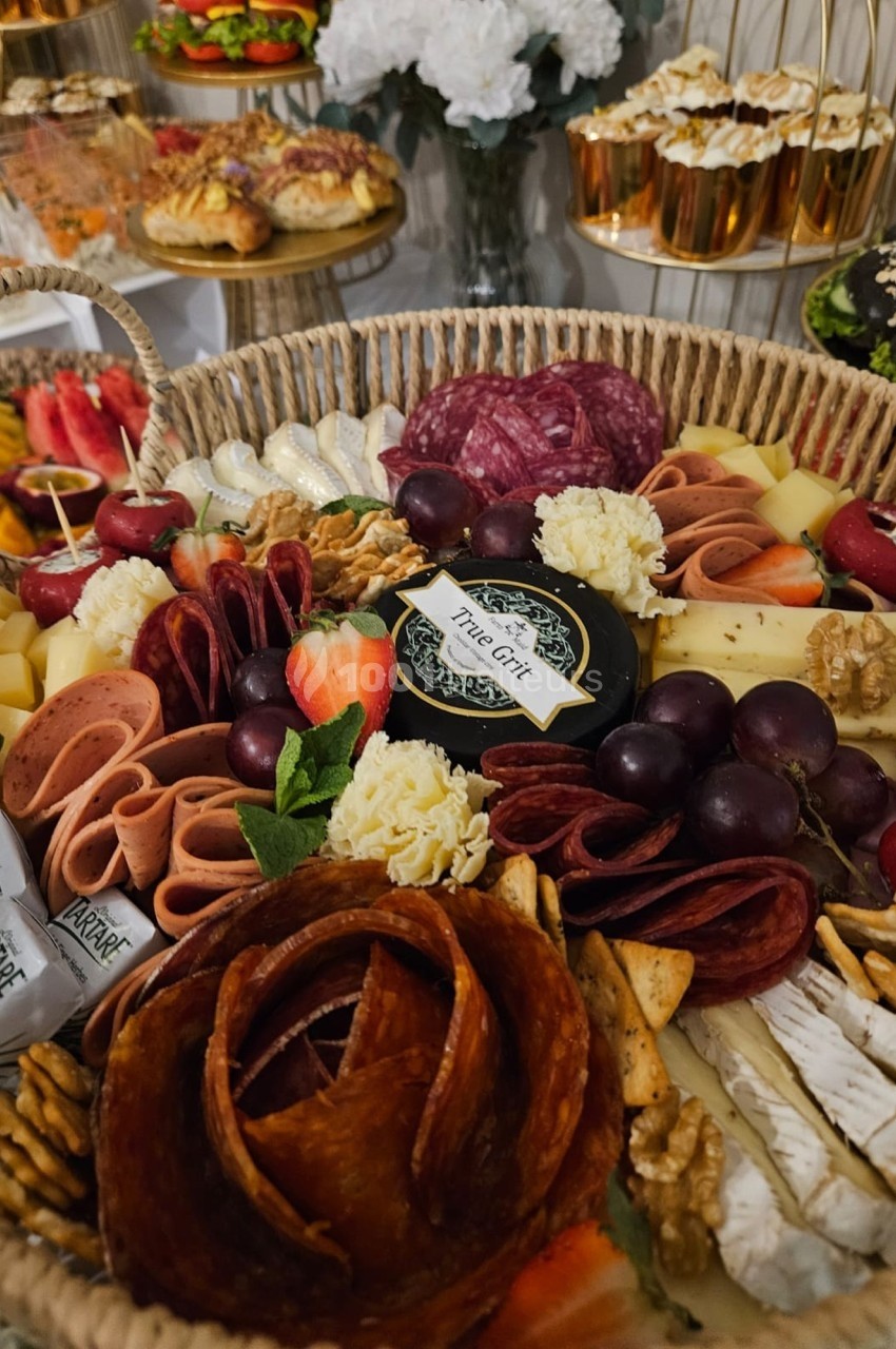 Plateau de charcuterie et fromages variés avec fruits, noix et crackers, présenté dans un panier en osier.