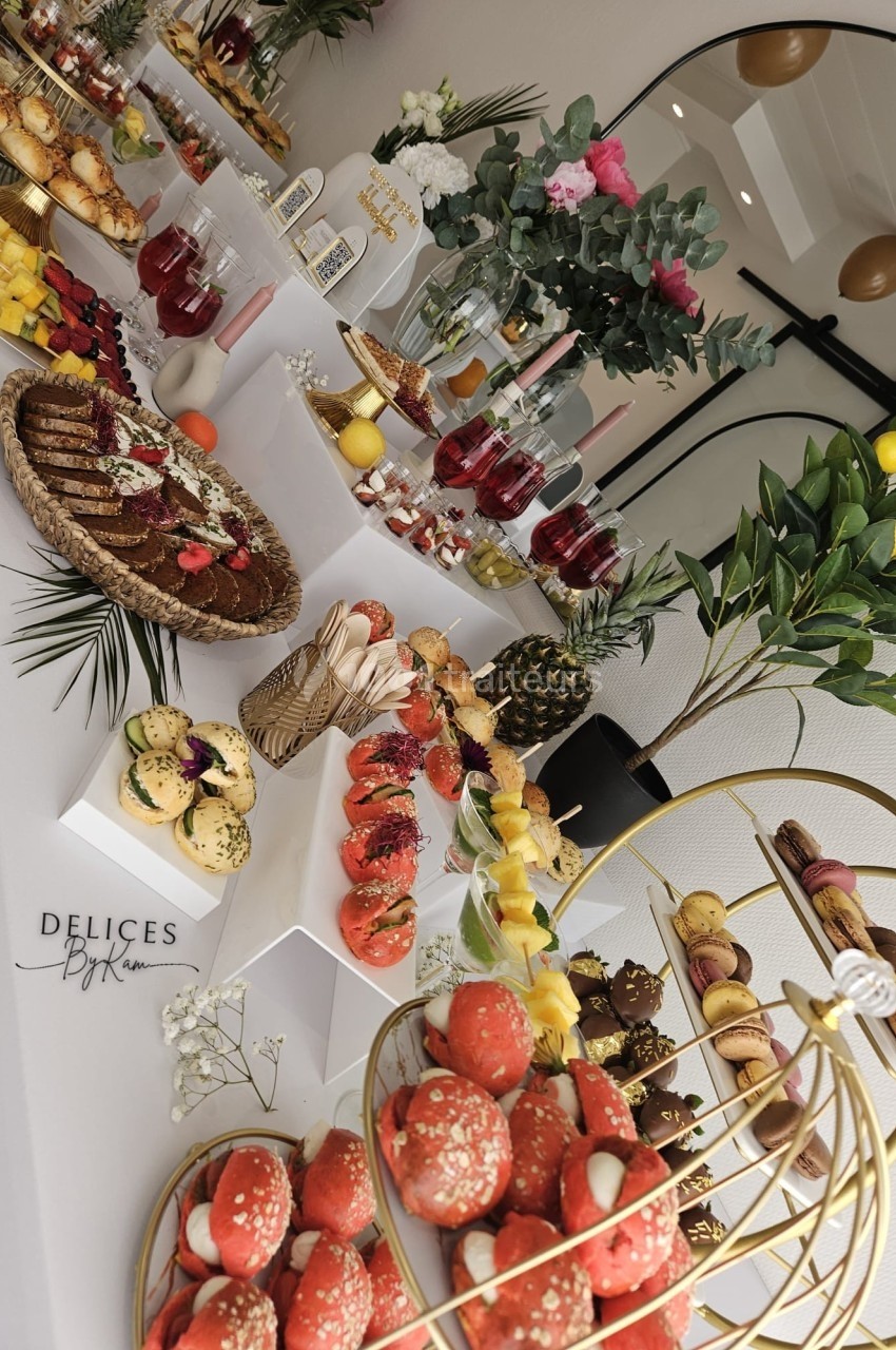 Table garnie de pâtisseries, fruits frais, boissons et décorations florales dans un cadre élégant.