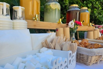 Buffet décoré avec des fleurs, fruits frais, verrines, mini-burgers et desserts, présenté sur une table élégante.