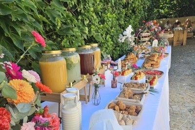 Buffet décoré avec des fleurs, fruits frais, verrines, mini-burgers et desserts, présenté sur une table élégante.