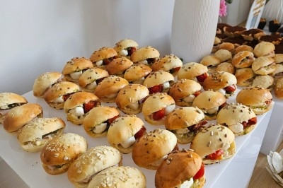 Buffet décoré avec des fleurs, fruits frais, verrines, mini-burgers et desserts, présenté sur une table élégante.