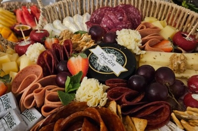 Buffet décoré avec des fleurs, fruits frais, verrines, mini-burgers et desserts, présenté sur une table élégante.