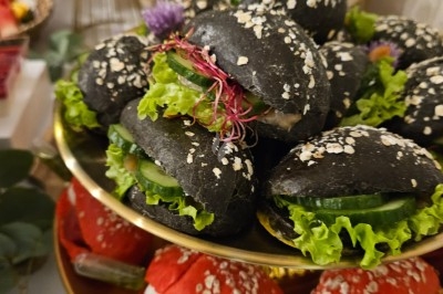 Buffet décoré avec des fleurs, fruits frais, verrines, mini-burgers et desserts, présenté sur une table élégante.