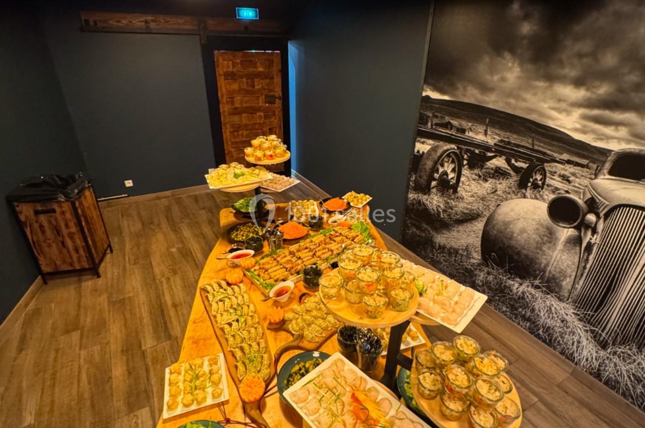 Table en bois garnie de divers plats et amuse-bouches dans une pièce sombre avec une décoration murale rétro.