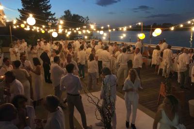 Façade éclairée d'un bâtiment nommé ’Le Yacht’ de nuit, avec des lumières bleues et un espace extérieur aménagé.