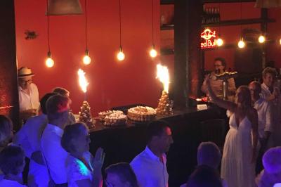 Façade éclairée d'un bâtiment nommé ’Le Yacht’ de nuit, avec des lumières bleues et un espace extérieur aménagé.