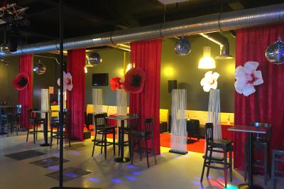 Façade éclairée d'un bâtiment nommé ’Le Yacht’ de nuit, avec des lumières bleues et un espace extérieur aménagé.