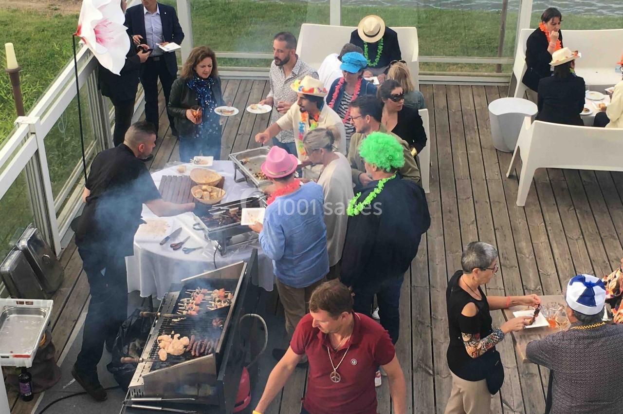 Groupe de personnes en extérieur autour d'un barbecue, certaines portant des déguisements festifs.