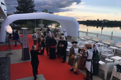 Façade éclairée d'un bâtiment nommé ’Le Yacht’ de nuit, avec des lumières bleues et un espace extérieur aménagé.
