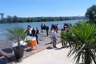 Façade éclairée d'un bâtiment nommé ’Le Yacht’ de nuit, avec des lumières bleues et un espace extérieur aménagé.