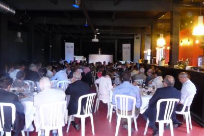 Façade éclairée d'un bâtiment nommé ’Le Yacht’ de nuit, avec des lumières bleues et un espace extérieur aménagé.