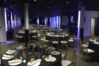 Façade éclairée d'un bâtiment nommé ’Le Yacht’ de nuit, avec des lumières bleues et un espace extérieur aménagé.